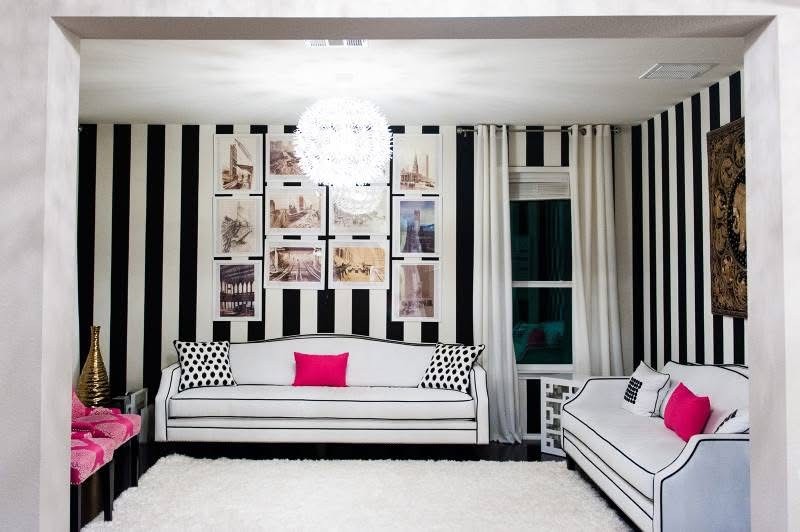 Living room with black and white striped walls, white sofas and hot pink pillows
