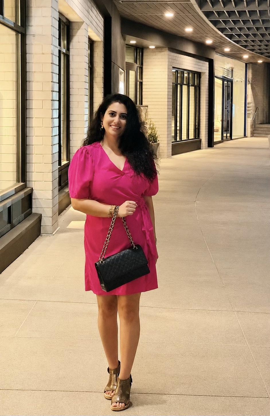 Founder in a hot pink wrap dress with a black quilted chain handbag